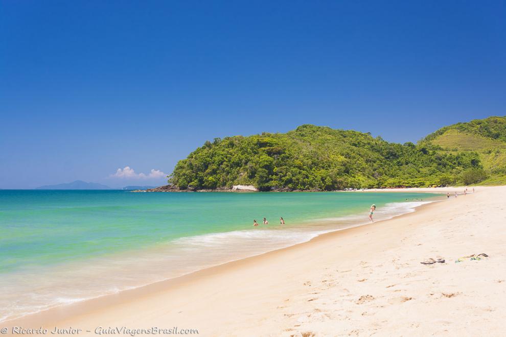 Imagem de uma família curtindo um dia ensolarado da Praia de Prumirim.